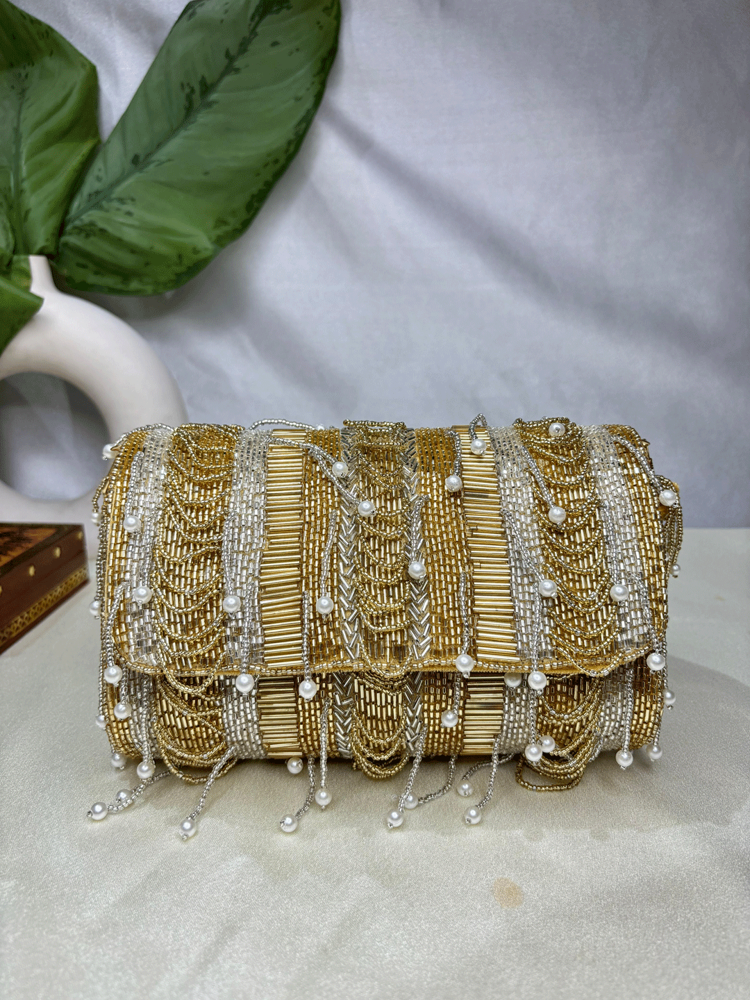 Gold beaded clutch bag with pearl accents on a neutral background