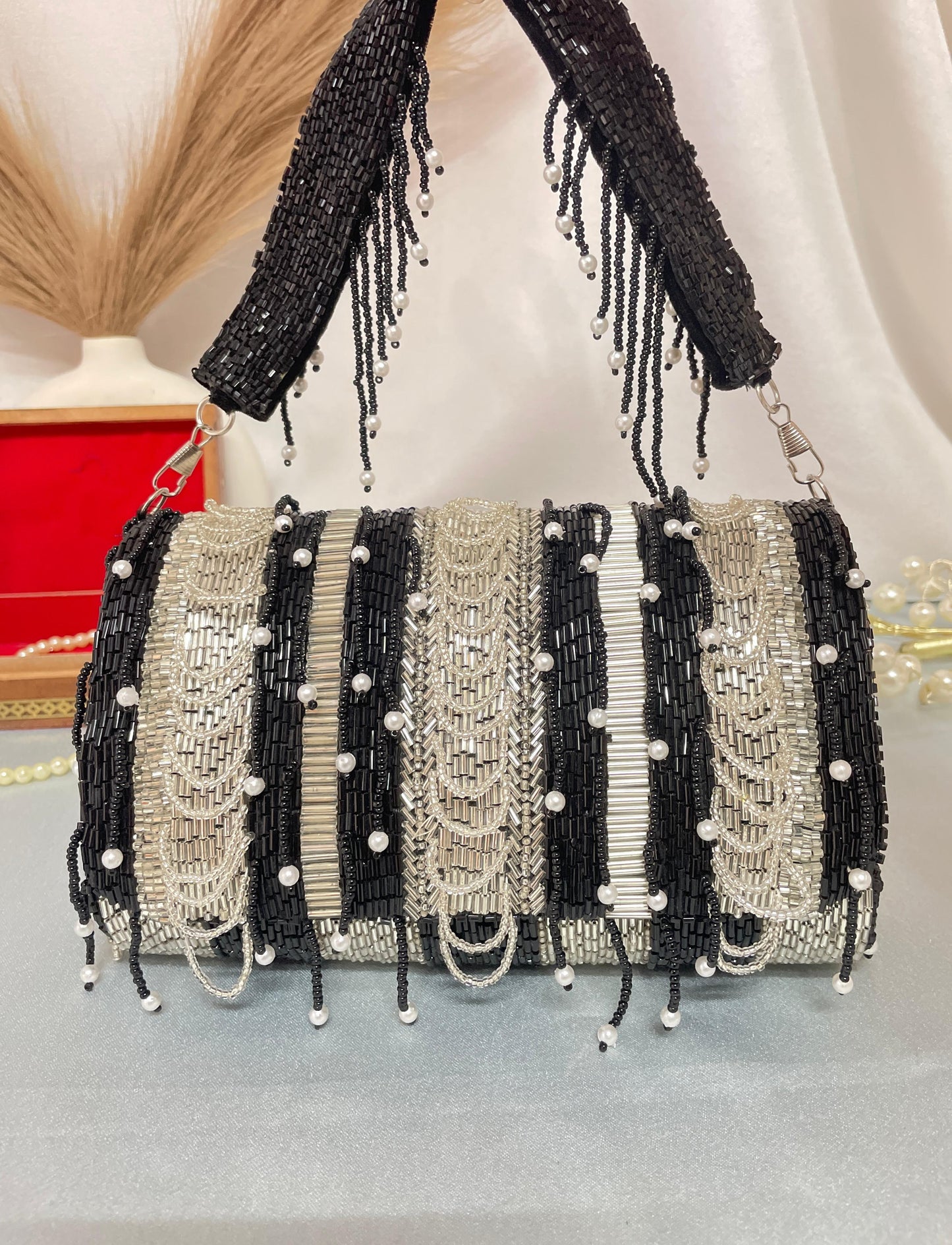 black beaded clutch bag with pearl accents on a neutral background