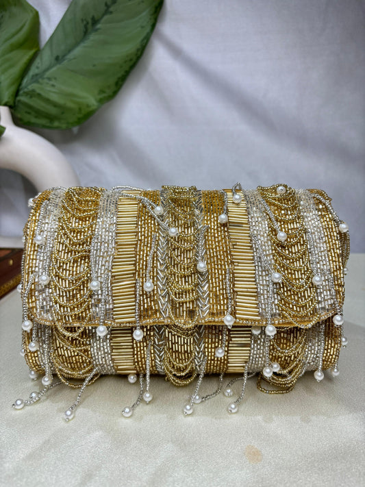 Gold beaded clutch bag with pearl accents on a neutral background