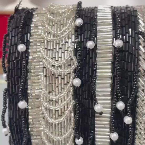 black beaded clutch bag with pearl accents on a neutral background