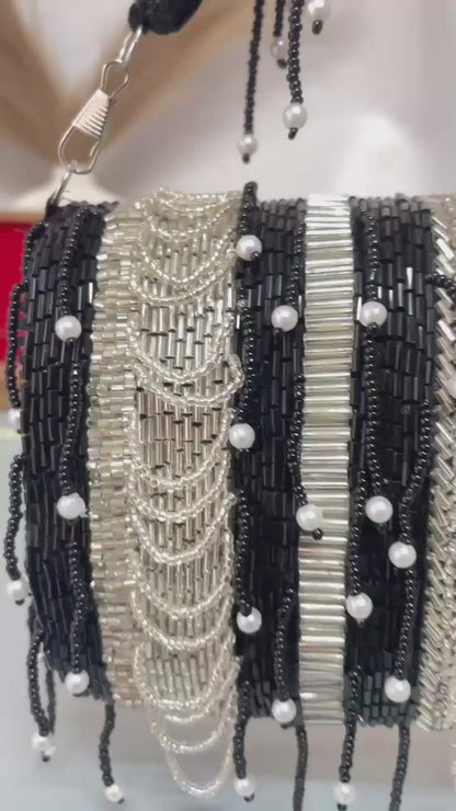 black beaded clutch bag with pearl accents on a neutral background